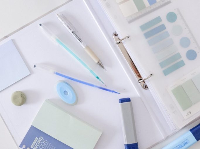 A collection of stationery items including a binder, pens, and various paper samples.